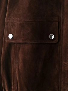 Detailed macro view of dark brown suede jacket texture and silver metal buttons