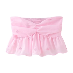 Détail d'un haut court sans bretelles rose avec broderie florale et ourlet volanté