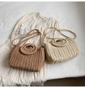 Dettaglio di borse in paglia intrecciata con manici rotondi e tracolle in marrone e beige