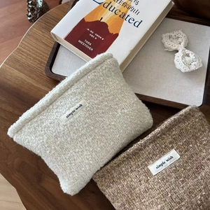 Close-up of tweed makeup bags in beige and brown with simple wish woven labels