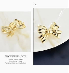 Detailed front and back view of a minimalist golden bow brooch in polished metal finish
