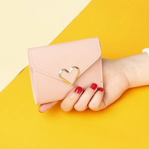 Pink short three-fold wallet for women with golden heart metal buckle held in hand