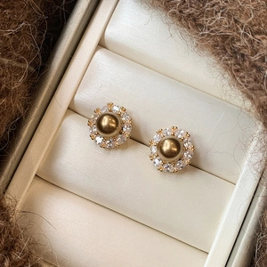 Close-up of vintage pearl earrings with gold-tone setting and pavé zircon details