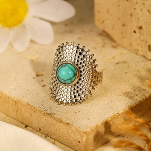 Macro shot of silver ring with turquoise stone on stone base with floral background