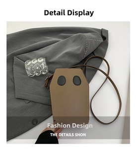 Detail of coffin-shaped brown crossbody bag featuring matte PU leather and eye-like patches