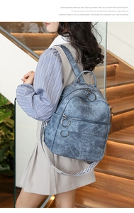Zaino blu rétro in finta pelle testurizzata con spallacci geometrici indossato da una modella