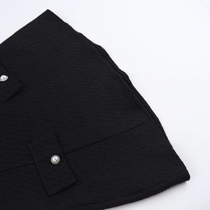 Close-up of black tweed fabric texture and decorative pearl buttons on the dress