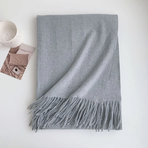 Close-up of soft grey cashmere-like scarf texture with elegant fringe detail