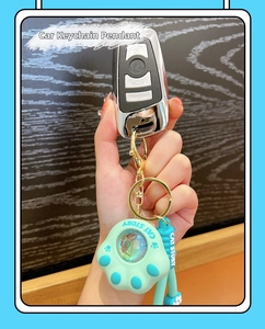 Detail of mint green cat paw keychain on car keys with blue CAT STORY wrist strap