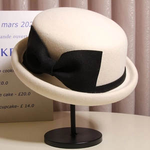 Detail of elegant wool cloche hat with black bow tie on a metal display stand