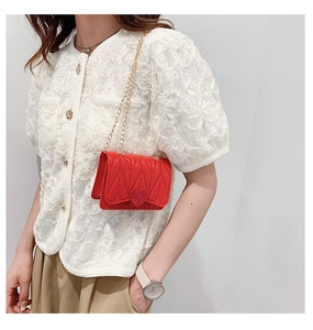 Close-up of red heart-shaped buckle and quilted texture on mini silicone bag