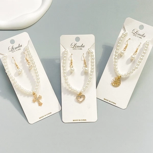 Flat lay of vintage pearl necklace sets with gold cross, heart, and moon star pendants