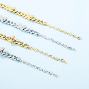 Close-up of gold and silver butterfly and pineapple charms on thick Cuban chain bracelets