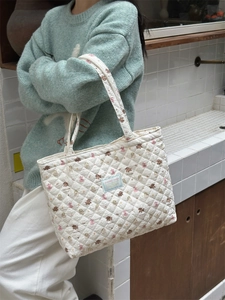 Close-up of quilted canvas bag with bear print and blue brand label detail