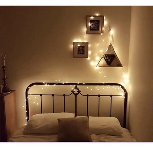 Warm white LED copper wire fairy lights wrapped on a bed frame for cozy home decoration