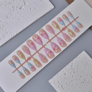 Mandel-Press-on-Nägel-Set mit 3D-Blumendesigns und Perlen auf einem Displayregal