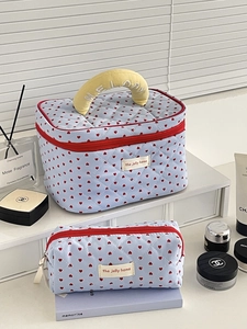 Macro detail of quilted blue makeup bags with heart patterns and yellow handles