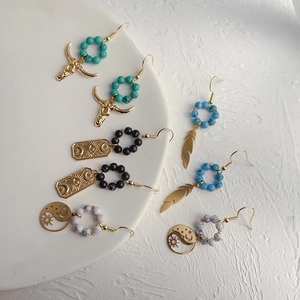 Detail of bohemian drop earrings with turquoise and bull head charms on a ceramic plate