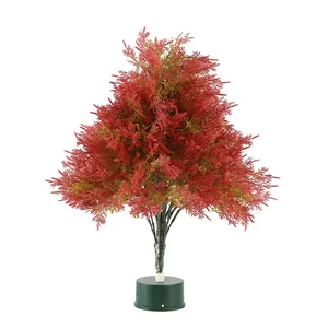 Mini artificial pine Christmas tree with orange-red needles and green circular base