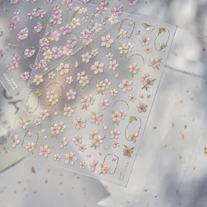 Macro detail of holographic cherry blossom nail decals with gold gilding and shell texture