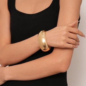 Polished gold wide cuff bracelet with a glossy mirror finish on a female model