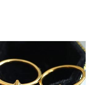 Close-up of two minimalist gold-colored bands displayed in a black velvet jewelry box