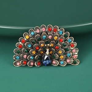 Macro shot of peacock brooch detail with vibrant multicolored rhinestones on green silk