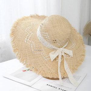 Detail of wide brim raffia sun hat with elegant white lace ribbon and frayed edges