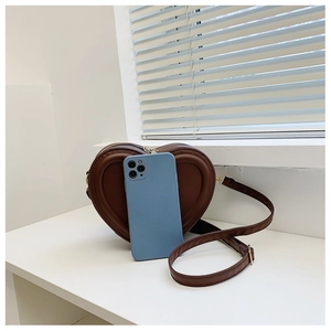 Borsa a tracolla in pelle marrone a forma di cuore rispetto a uno smartphone per le dimensioni