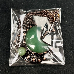 Macro detail of vintage green aventurine crescent moon necklace with bronze metalwork