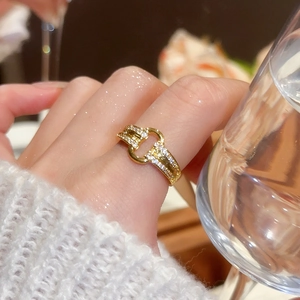 Close-up of 18k gold horsebit ring with sparkling zircons worn by a model in warm light