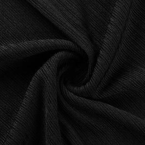 Gros plan sur un tissu plissé noir montrant une texture verticale et un drapé élégant