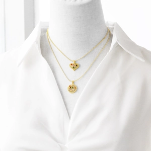 Detail of layered gold necklaces with colorful gemstone heart and round pendants