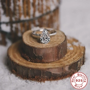 Macro view of pear-cut gemstone engagement ring in 925 sterling silver on rustic wood