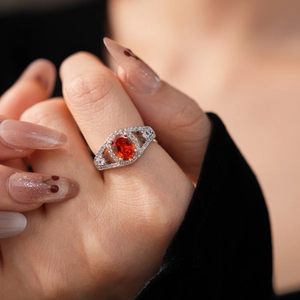Macro detail of oval orange gemstone ring with zircon accents on a model's hand