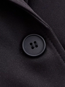 Vue macro détaillée du tissu noir tissé du blazer avec un bouton assorti à quatre trous