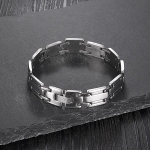 Close-up of silver H-link stainless steel bracelet with brushed finish on dark stone