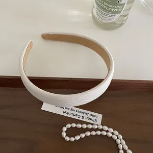 Close-up of a white padded headband with diagonal fabric texture on a vintage tray