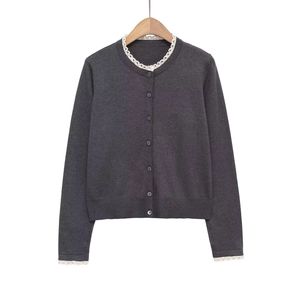 Gilet en tricot gris foncé avec bordure en dentelle blanche et boutons sur fond blanc