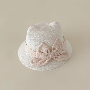 Detail of baby straw hat with woven texture, cat ears and a large pink bow decoration