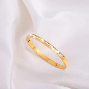 Polished gold stainless steel bangle with Roman numerals and crystals on white silk