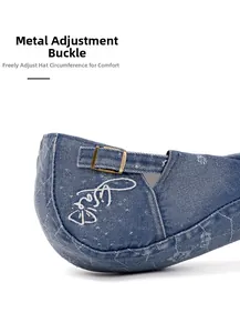 Detail of adjustable metal buckle on vintage washed denim beret with white embroidery