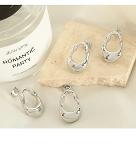 Close-up of four irregular geometric silver earrings on elegant beige stone props