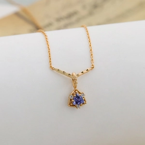 Dettaglio di gemma viola a triangolo su collana in argento placcato oro 14K