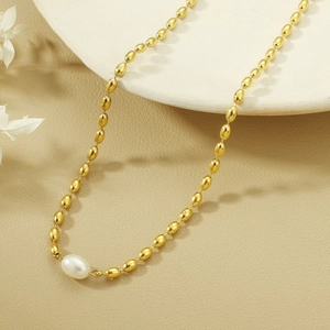 Detailed macro view of gold-tone oval bead necklace with a white freshwater pearl accent