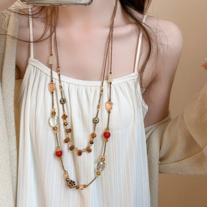 Close-up of vintage multi-layer beaded necklace with amber and crimson pendants on model