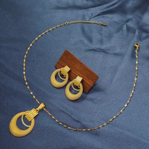 Detail of gold geometric earrings and necklace set with textured mesh on blue silk fabric