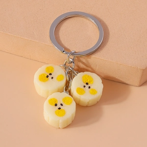 Macro detail of realistic banana slice keychain with three yellow resin charms on silver ring