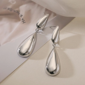 Elegant silver teardrop earrings with polished metal finish on a textured background