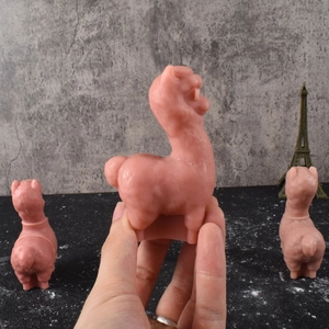Detail of pink alpaca candle with sunglasses shown in hand for size perspective